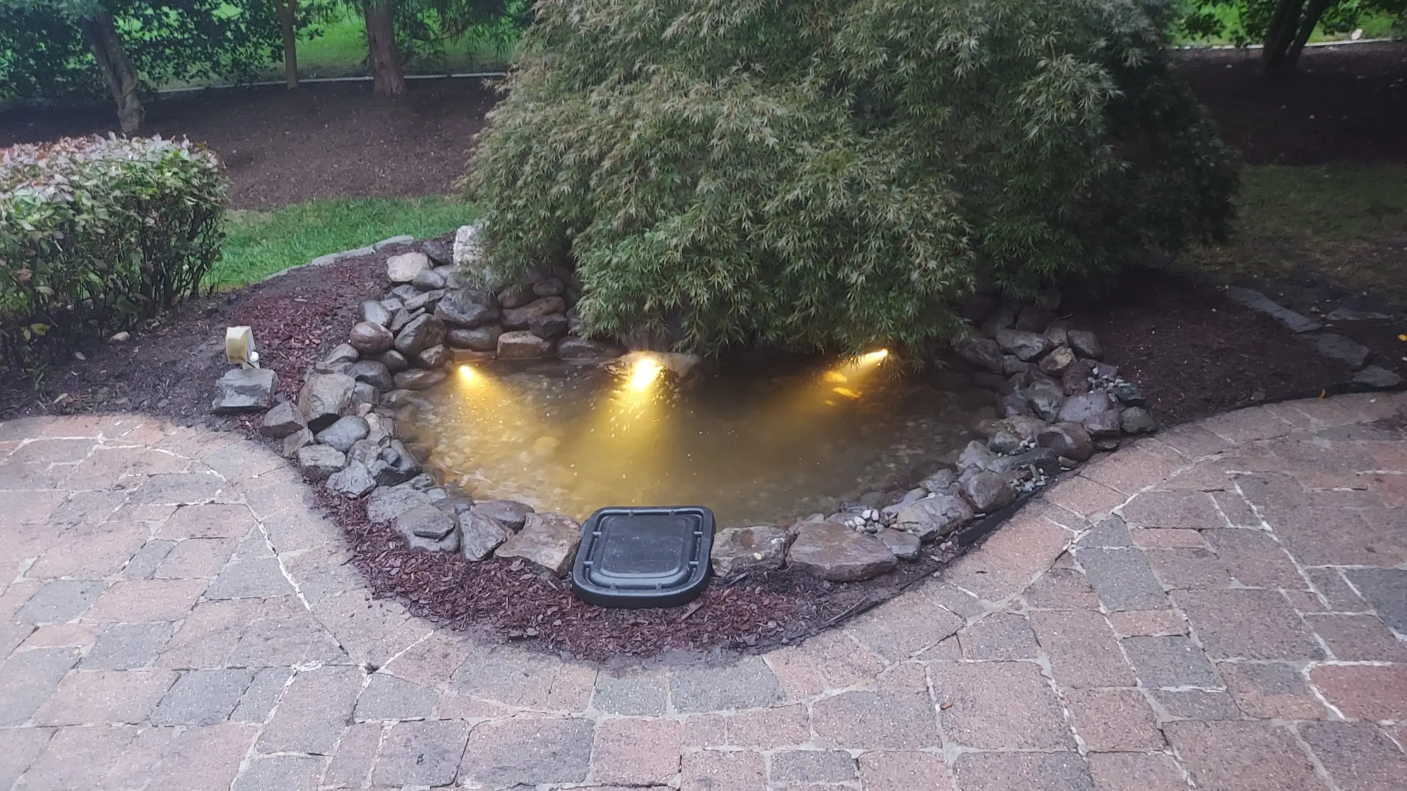 A pond constructed in Chantilly, Virginia. This pond featured aquascape lights, a new skimmer and new Biofalls.
					Unlike the traditional flat field stones used in pond construction, round rocks and boulders were used to build the walls of this pond.